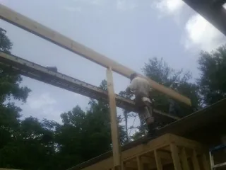 Carpenter setting a ridge beam over a new addition frame — Ice Dam Removal by Roofing Brothers in Philipsburg
