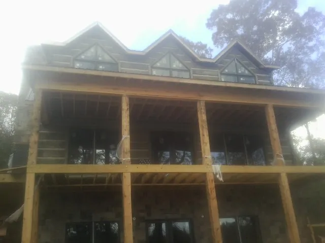 Dormers and porch framing on a large log home under construction — Roof Coating work by our crew in Philipsburg