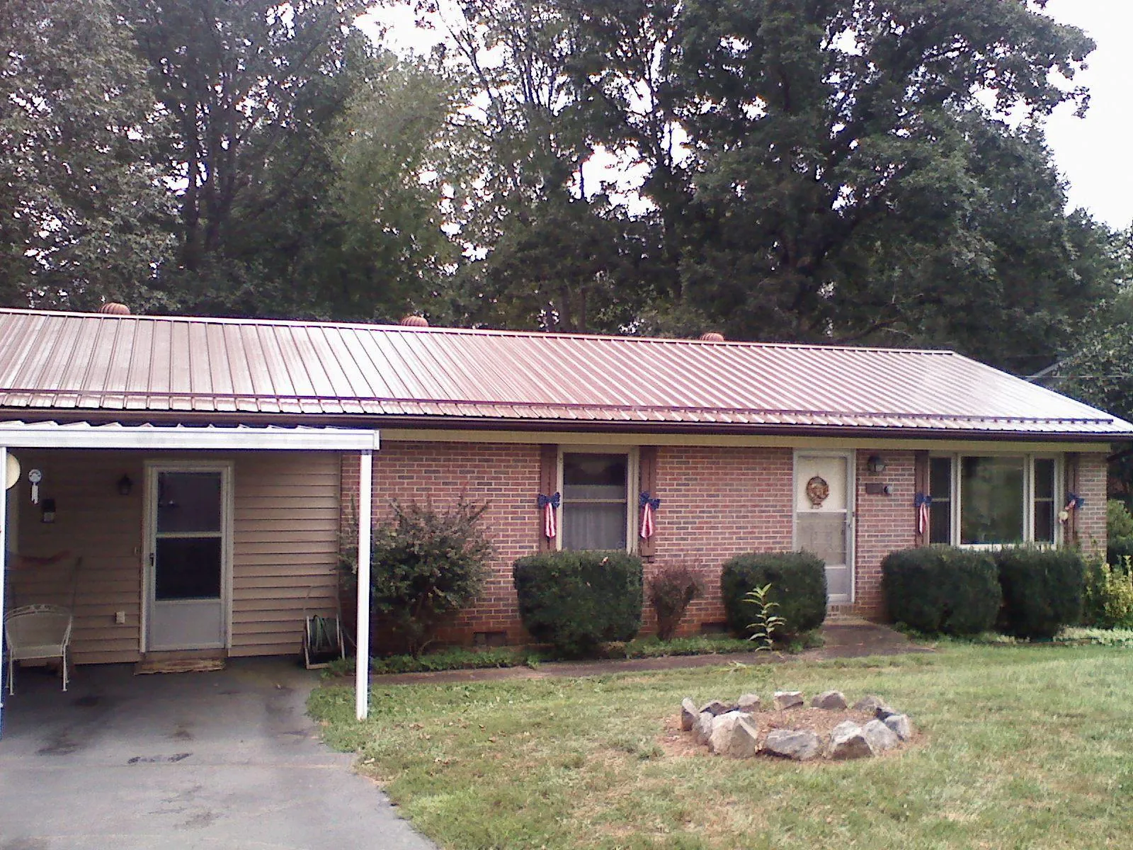 Bronze metal roof and carport on a brick ranch home — Roof Repair work by our crew in Philipsburg