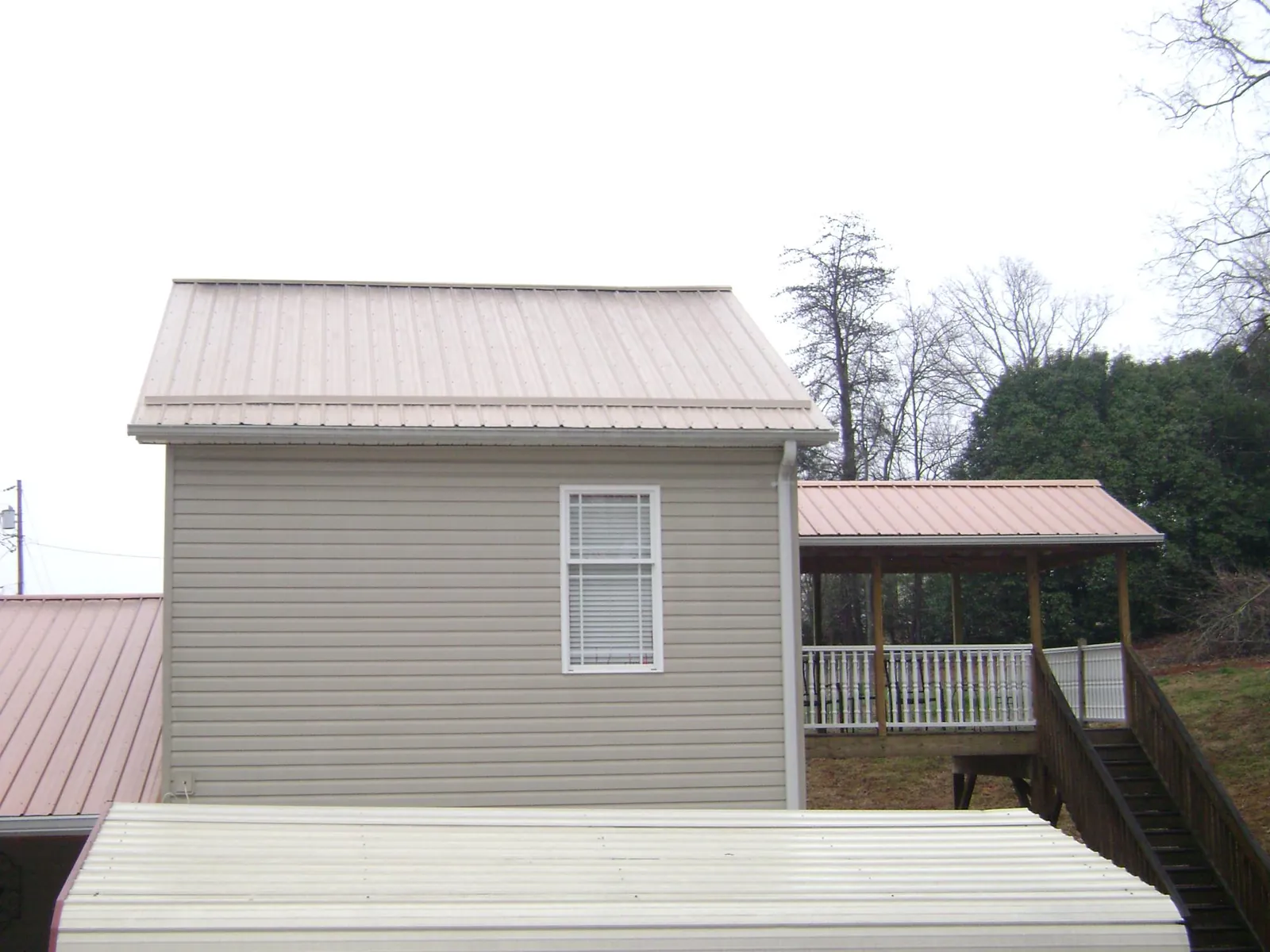 Tan metal roofs on a two story addition and attached porch, from a Roof Replacement job in Philipsburg